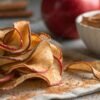 Closeup of homemade apple chips with cinnamon on a rustic table.