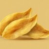 Dried mango slices are stacked loosely together, presenting a chewy fruit snack against a soft amber background for food advertising.