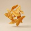 Healthy organic dried mango flakes floating in a clean studio shot with soft lighting on a neutral beige backdrop.