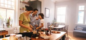 Playful dad feeding his son a slice of bread in the kitchen