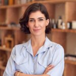 Portrait Of Female Owner Of Gift Store Standing In Front Of Shelves With Cosmetics And Candles