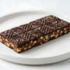 Rich Chocolate Nut Butter Crunch Bar Artfully Presented on a White Plate